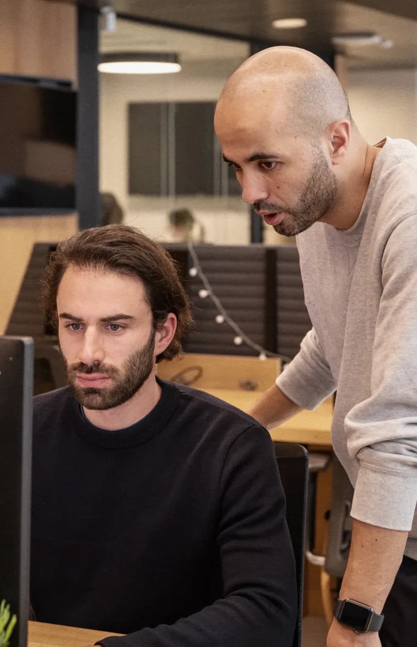 Two team members at a screen, in the office